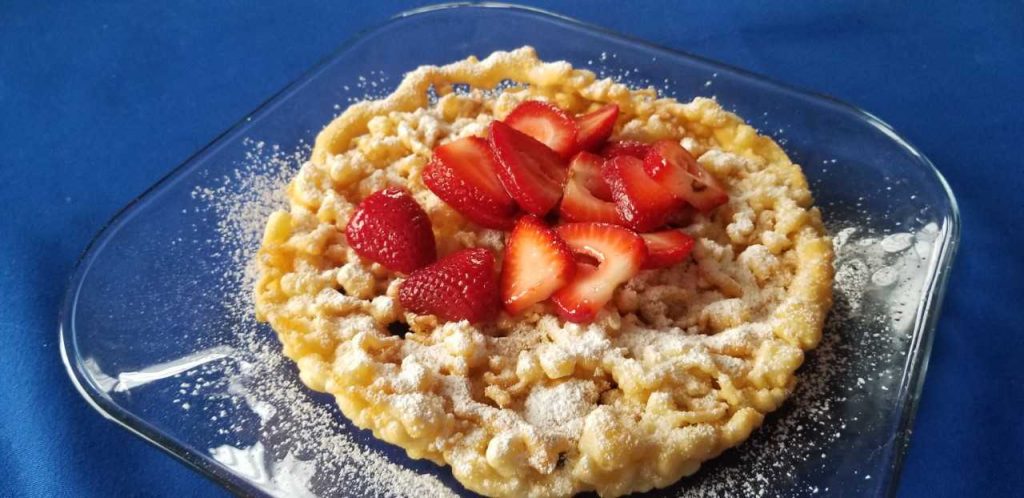 Funnel Cake with powdered sugar and strawberries on top