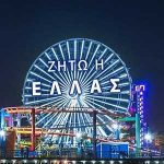 The greek flag and slogans for independance displayed in lights on the Ferris wheel