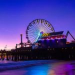 A multi-colored Ferris wheel reflects off the water by the Santa Monica Pier | Photo by Scott Trento, Upsplash