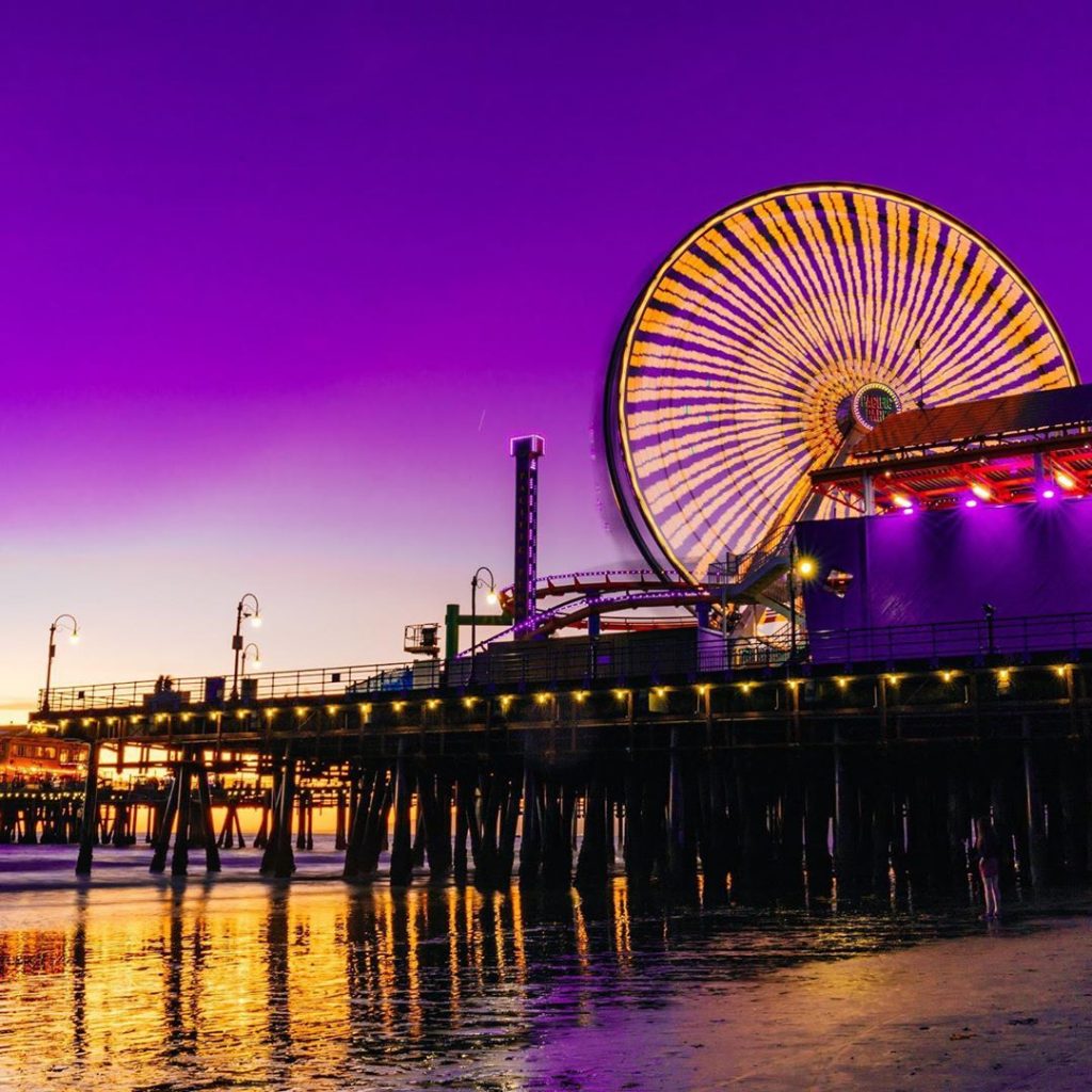 The Ferris wheel in Santa Monica in yellow on a pink and purple sky | Photo by @michaeltsirakis