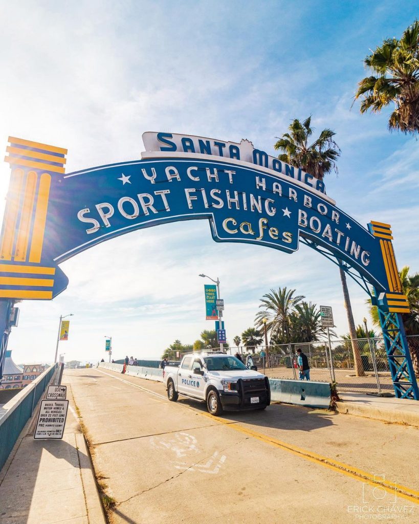 A Santa Monica Pier Harbor Patrol truck under the historic Santa Monica Pier and Yacht Harbor Sign.