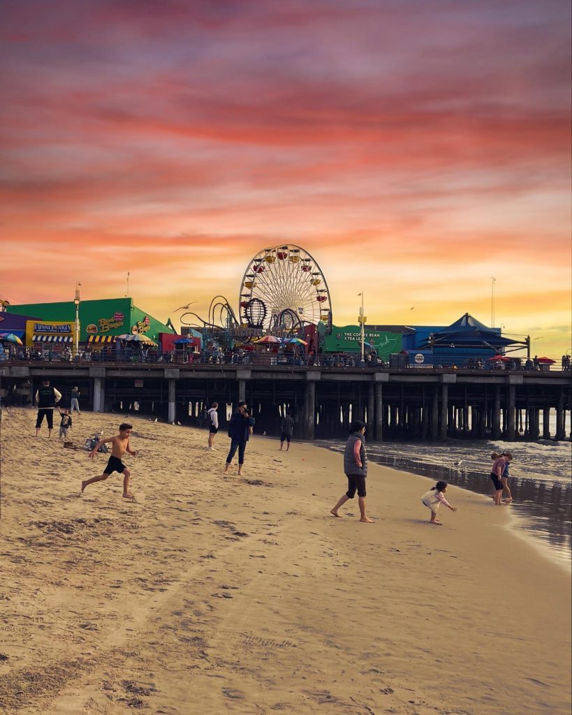 Beach goers run into the water by the Santa Monica Pier