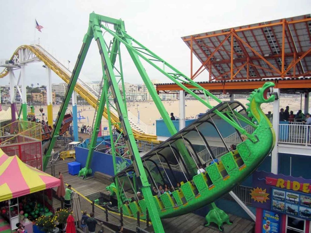 The bright green Sea Dragon ride swings with riders at the Santa Moncia Pier