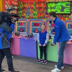 KTLA's Andy Riesmeyer interviews a young guest in front of the Whac-a-mole game at Pacific Park on the Santa Monica Pier